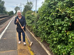 A person with a broom sweeps a station platform