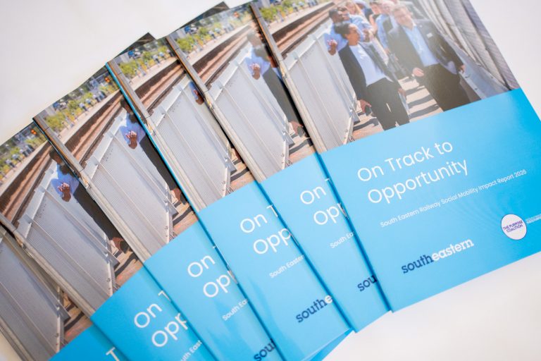 Copies of the "On Track to Opportunity" report fanned out on a table.