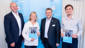 A group of people including, Justine Greening MP, Steve White, Managing Director of Southeastern, and Elliott Frost, Southeastern. They are posing for a picture with Justine and Elliott holding copies of the "On Track to Opportunity" report.