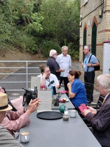 A group of people enjoying drinks while sat round a table outside the Sinal Box Cafe at Hollingbourne