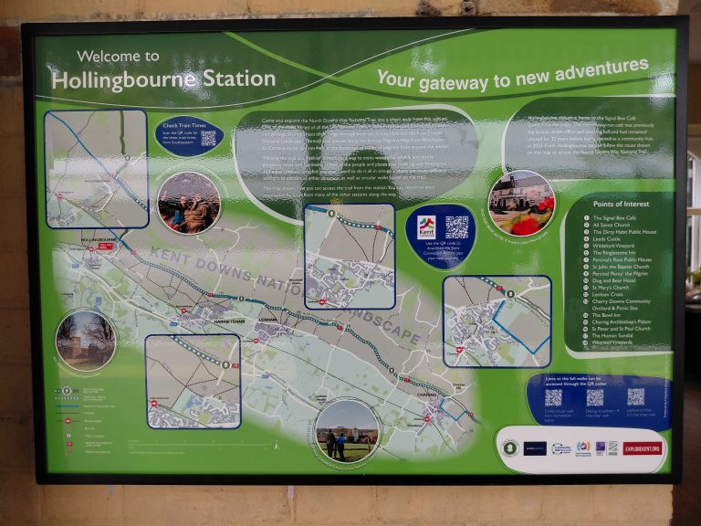 An information board "Welcome to Hollingbourne station - Your gateway to new adventures". Map display of the North Downs Way between Hollingbourne and Charing with connecting walking routes to local stations, key points of interest and qr codes to access further information.