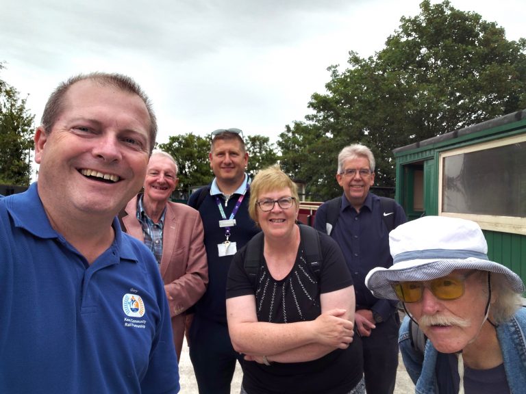 Selfie of Gary, Jonathan. Luke. Angela, Matt and Jackie with train carriages behind.