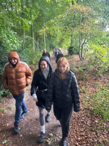 A group of people walk along a gravel path in woodland.