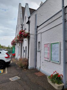 The exterior of Queenborough station, with colourful planters and hanging baskets