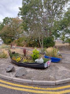 Colourful wooden rowing boats repurposed as planters, filled with flowers and shrubs