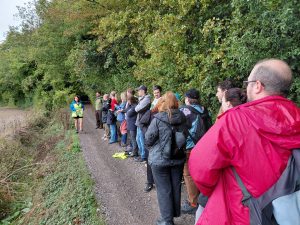 Therese talks to a group of people on a woodland path.