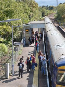 View form a footbridge at a station. A group of people are boarding a train.