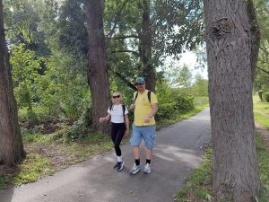 Roxy and James walk along an asphalt path between trees