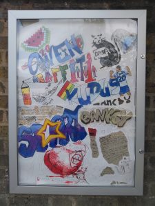 A display cabinet mounted on a wall. The cabinet contains a variety of graffiti styled artwork and some notes on the history of the genre.