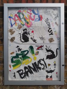 A display cabinet mounted on a wall. The cabinet contains a variety of graffiti styled artwork and some notes on the history of the genre.